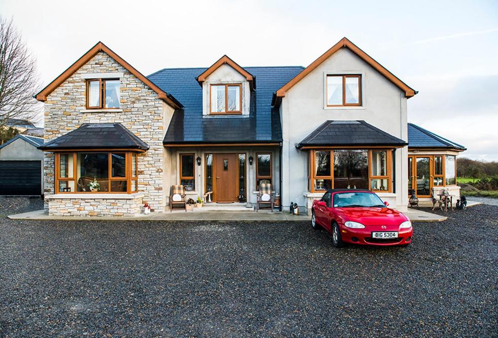 un coche rojo estacionado frente a una casa en Cherrytree House B&B, en Moville