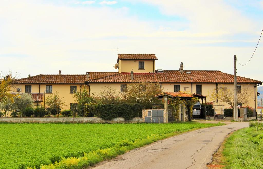 una casa grande con un campo verde junto a una carretera en Mina House, en Campi Bisenzio