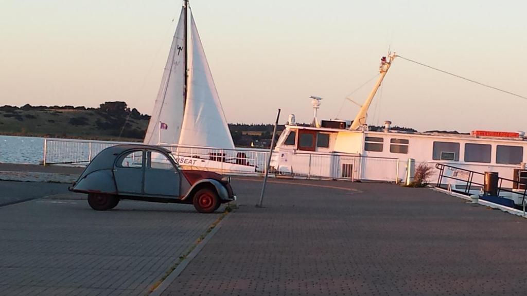 ein kleines Auto, das auf einem Dock neben einem Boot parkt in der Unterkunft Ferienhaus "Sommerbrise" in Gager