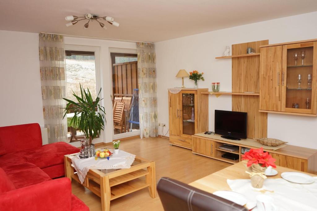 ein Wohnzimmer mit einem roten Sofa und einem TV in der Unterkunft Ferienwohnung Jungbauernhof in Alpirsbach