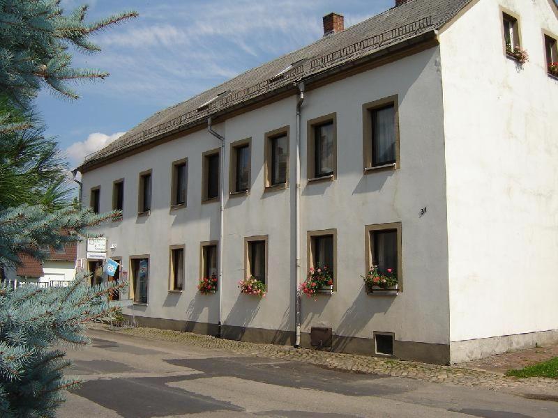 a white building with windows and flower boxes on it at Zimmervermietung-Heide-Fiege in Hartmannsdorf