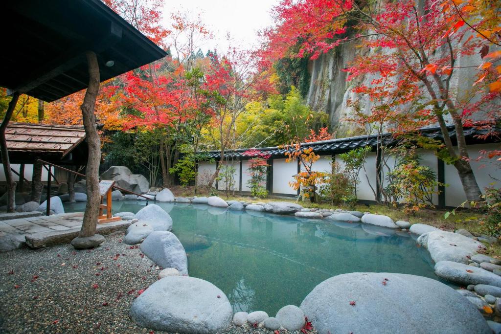 a pool of water with rocks in front of a building at Kurokawa-So in Minamioguni