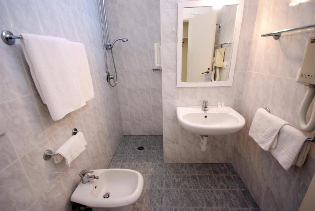 a white bathroom with a sink and a toilet at Hotel Dino in Capoliveri