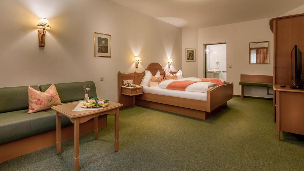 ein Hotelzimmer mit einem Bett und einem Sofa in der Unterkunft Tennis Golf Hotel Höllrigl in Kottingbrunn