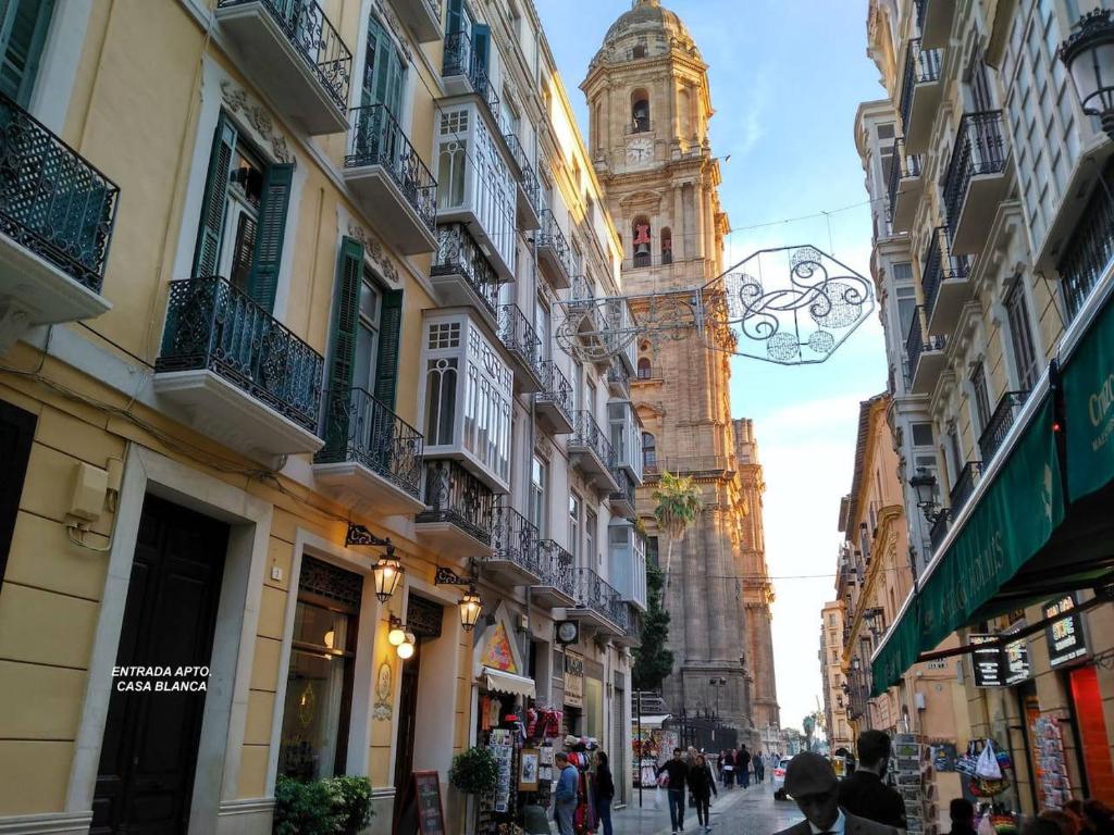 una strada cittadina con una torre dell'orologio in lontananza di Luxury Catedral a Málaga