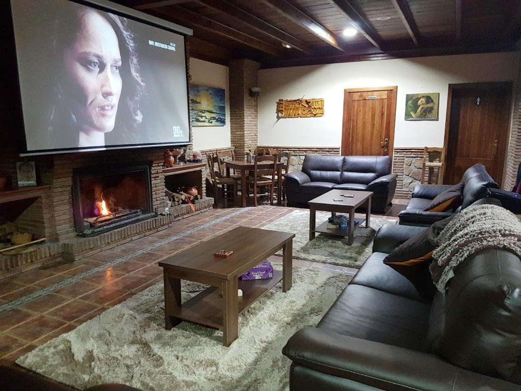 salon z kominkiem i dużym ekranem w obiekcie Hospedería Los Cahorros w mieście Monachil