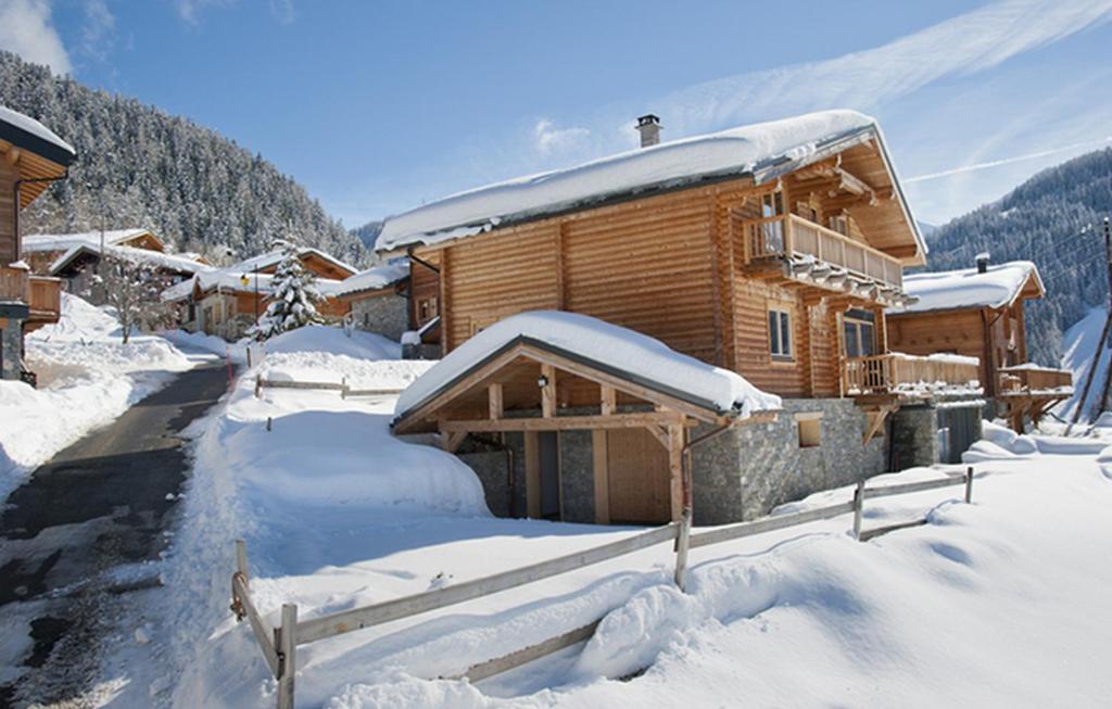 una cabaña de madera en la nieve con una carretera en Odalys Chalet Mont Soleil, en Mâcot La Plagne