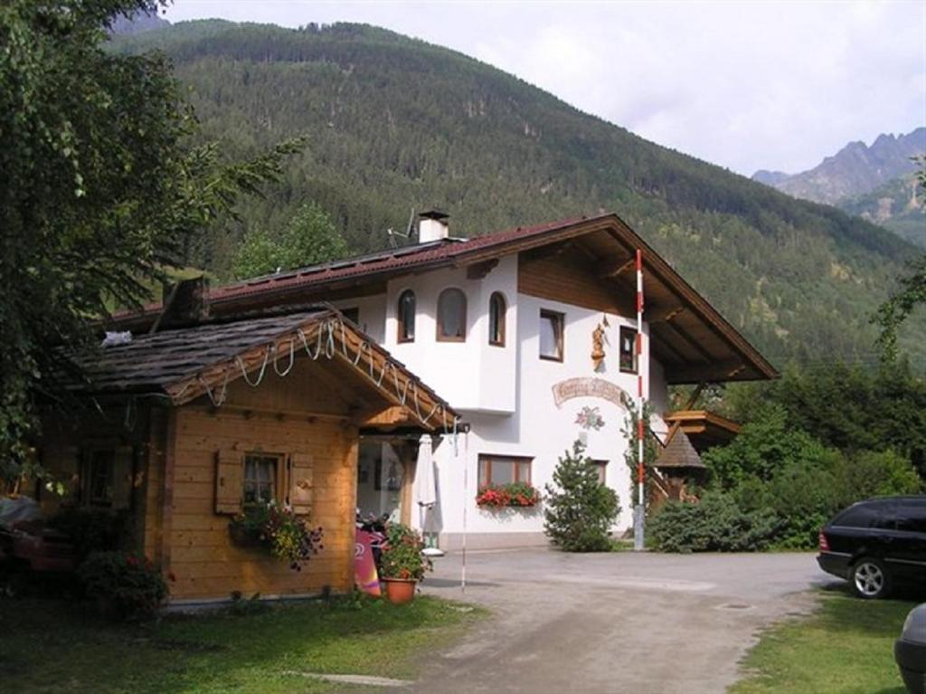 una casa en las montañas con un coche aparcado delante en Camping Gasthof Zirknitzer, en Großkirchheim