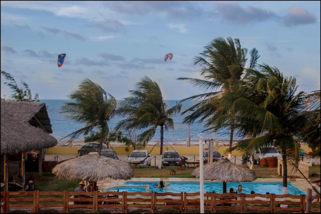 uma praia com palmeiras e papagaios voando no céu em Pousada Amor a Mar em Icapuí