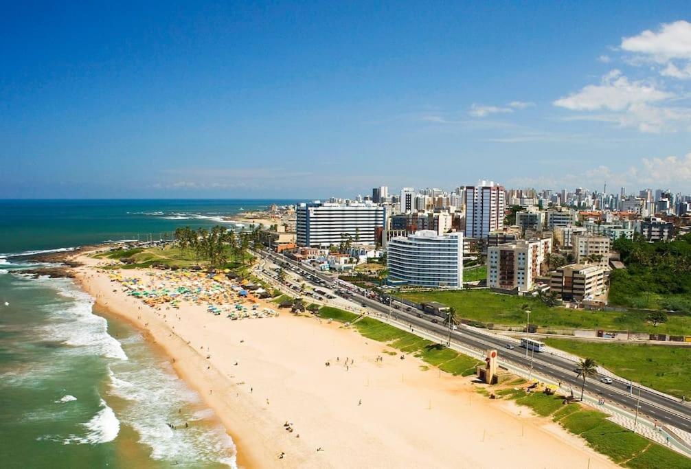 einen Strand mit Menschen und dem Meer und einer Stadt in der Unterkunft Apartamento na praia de Armação in Salvador