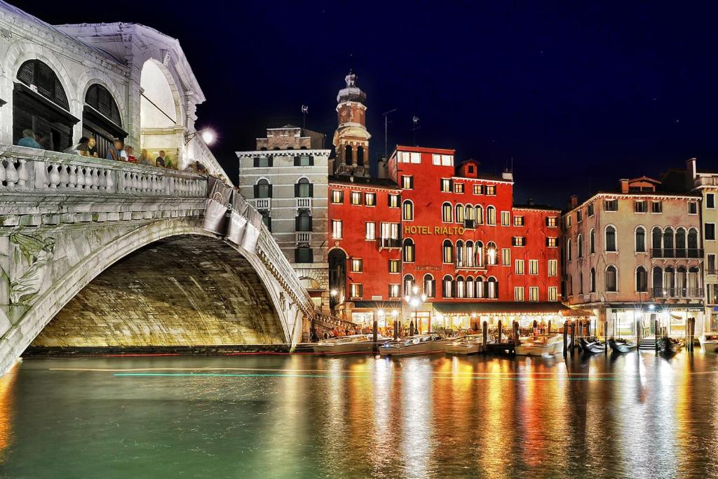 un puente sobre un río en una ciudad por la noche en Hotel Rialto, en Venecia