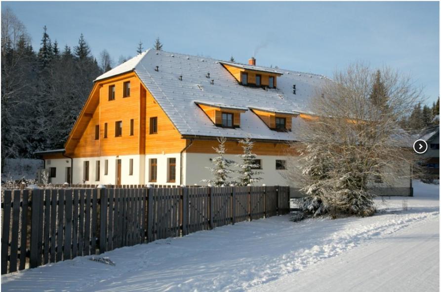 a large wooden house with a fence in the snow at Chata u Tří Sluk in Modrava