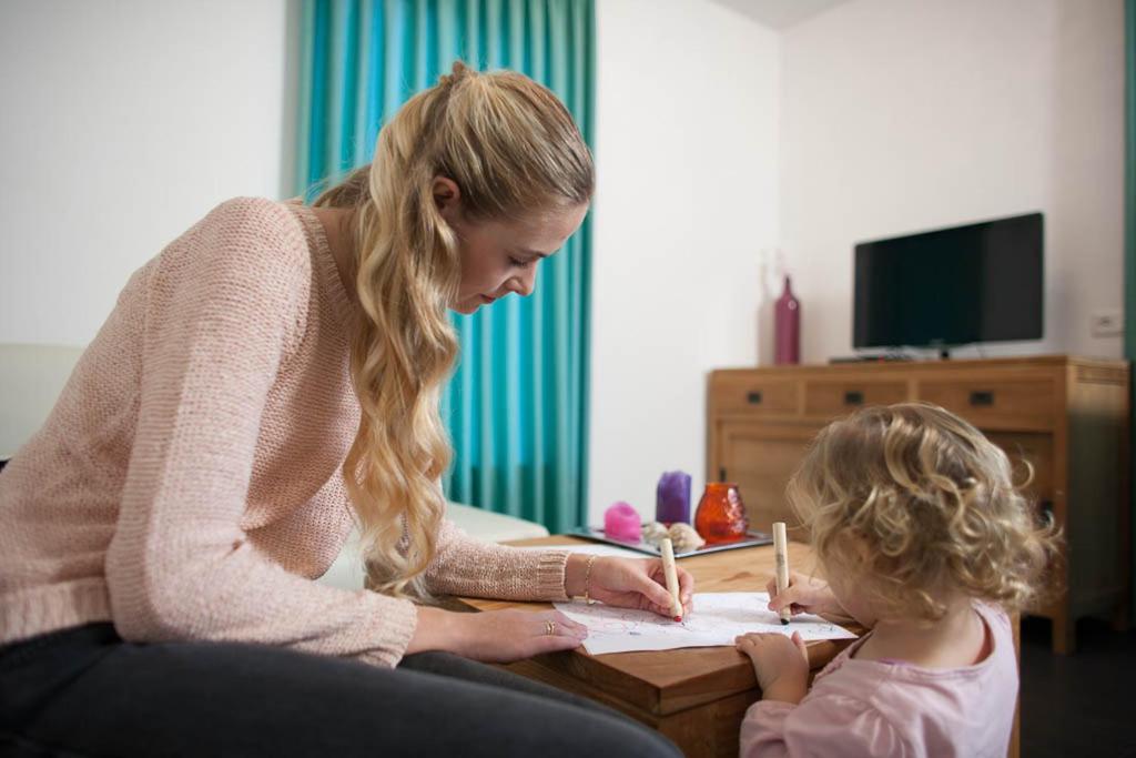 a woman sitting next to a little girl writing at Appartement de Runsvoort in Helvoirt