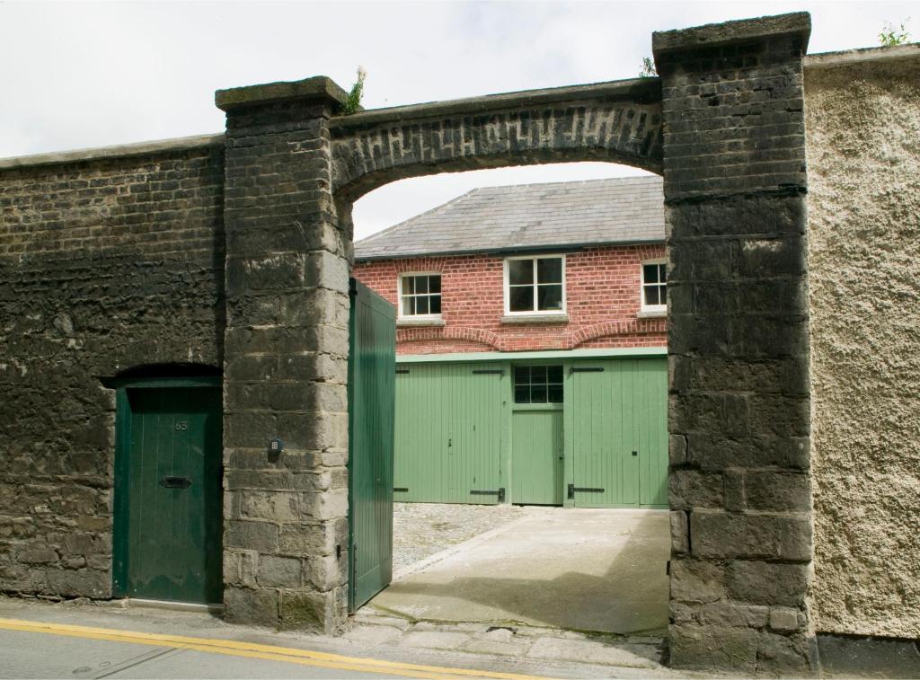 um edifício de tijolos com portas verdes e uma garagem em Merrion Mews em Dublin
