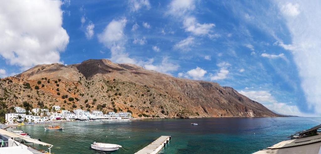 a group of boats docked in the water next to a mountain at Daskalogiannis Hotel in Loutro