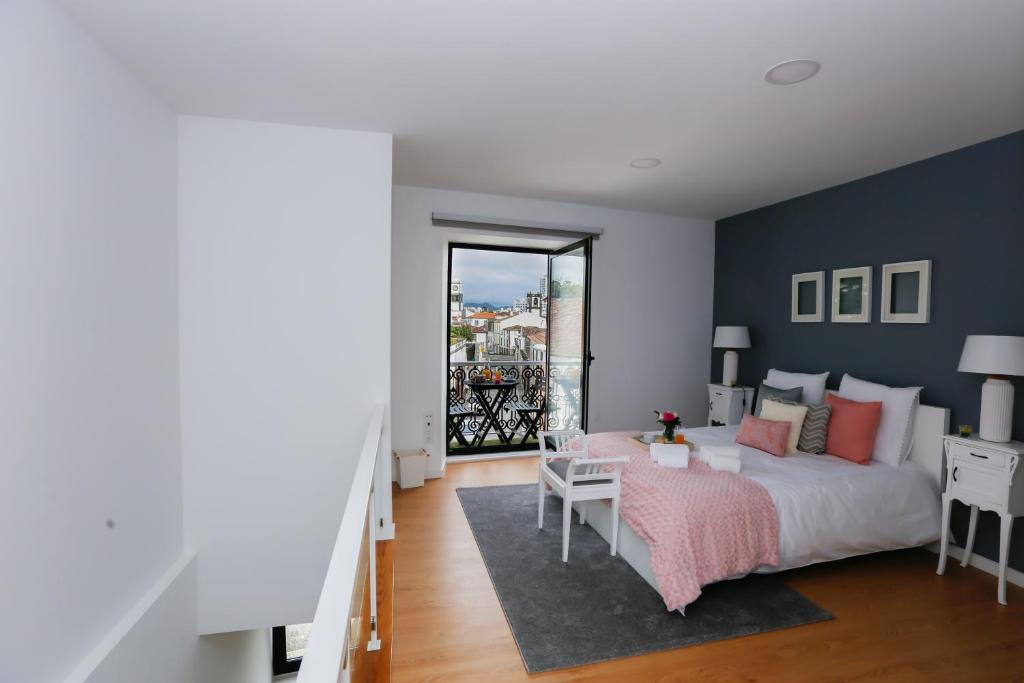 1 dormitorio con cama blanca y pared azul en 2 Towers Apartment, en Ponta Delgada