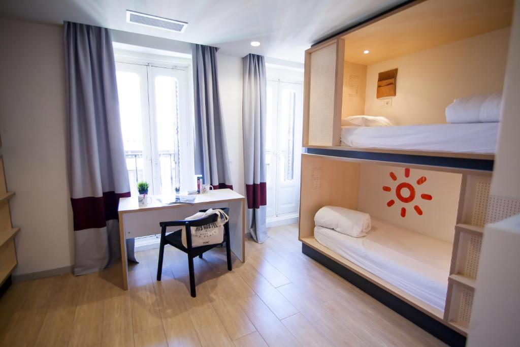 Mały pokój z łóżkiem piętrowym i biurkiem w obiekcie Toc Hostel Madrid w Madrycie