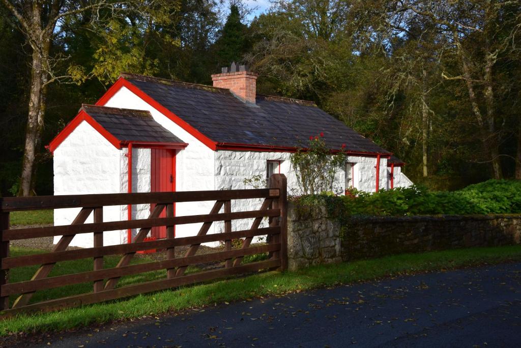 a red and white house behind a fence at Railway Crossing Cottage in Murlas Bridge
