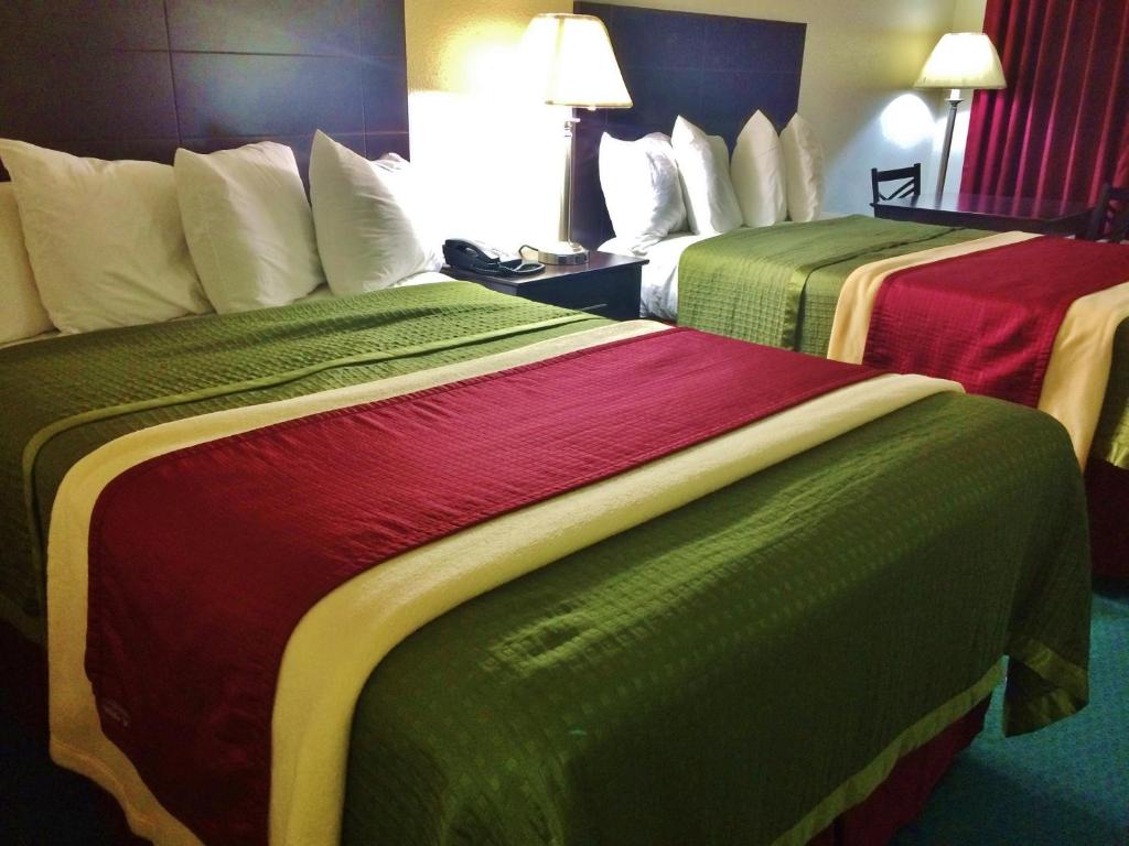 two beds in a hotel room with green and red blankets at Travel Inn & Suites in Atlanta