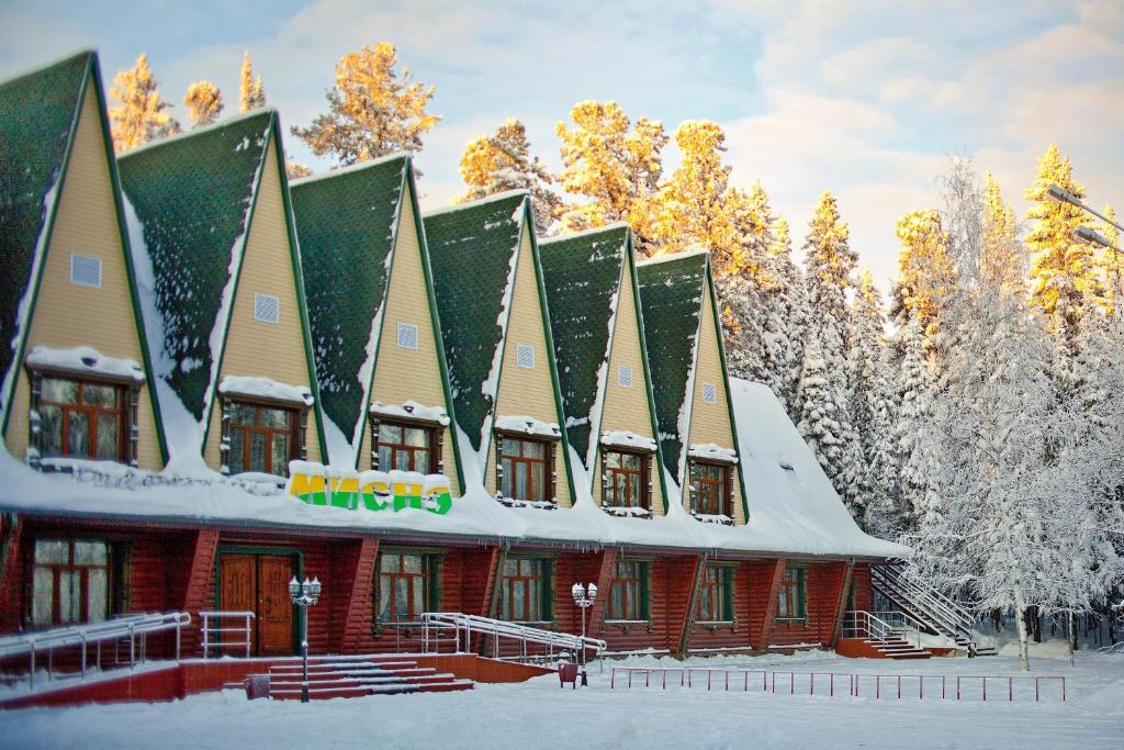 un edificio cubierto de nieve con árboles en el fondo en Hotel Misne, en Khanty-Mansiysk