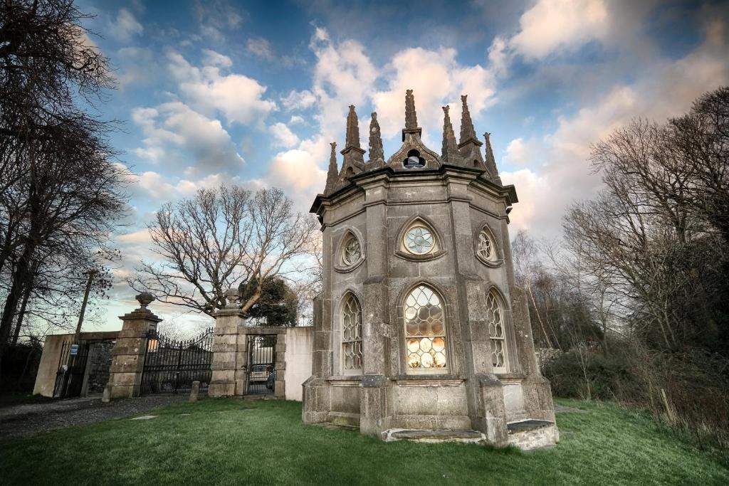 um edifício antigo com uma torre de relógio na relva em Batty Langley Lodge em Leixlip