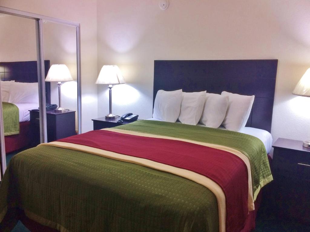 a bedroom with a large bed with a green and red blanket at Travel Inn & Suites in Atlanta
