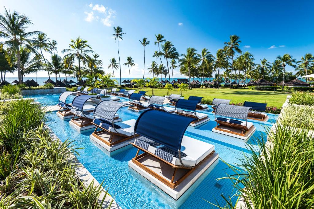 a row of lounge chairs in a pool at a resort at Tivoli Ecoresort Praia do Forte in Praia do Forte