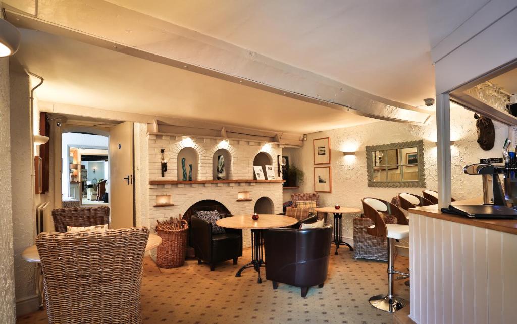 a dining room with a table and a fireplace at Combe House Hotel in Holford
