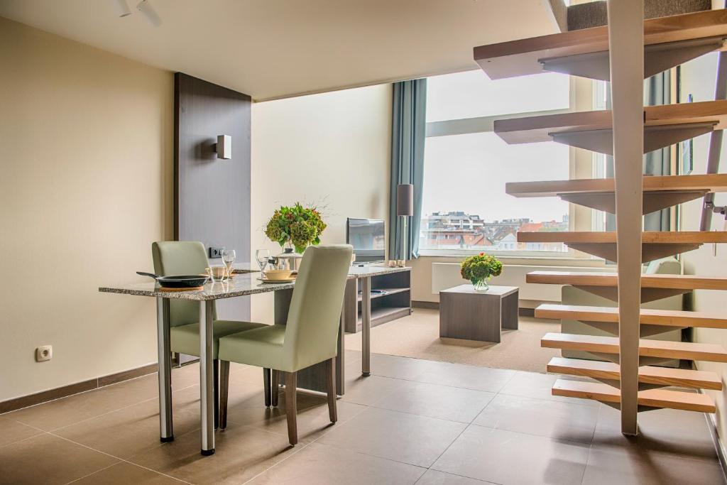 a dining room with a table and a spiral staircase at Arass Hôtel & Business Flats in Antwerp