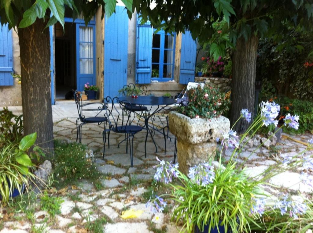 um pátio com uma mesa e cadeiras em frente a uma casa azul em Aux Pots Bleus em Nissan-lez-Enserune