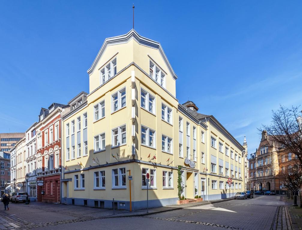 un edificio alto amarillo en una calle de la ciudad en City Hotel Stolberg, en Stolberg