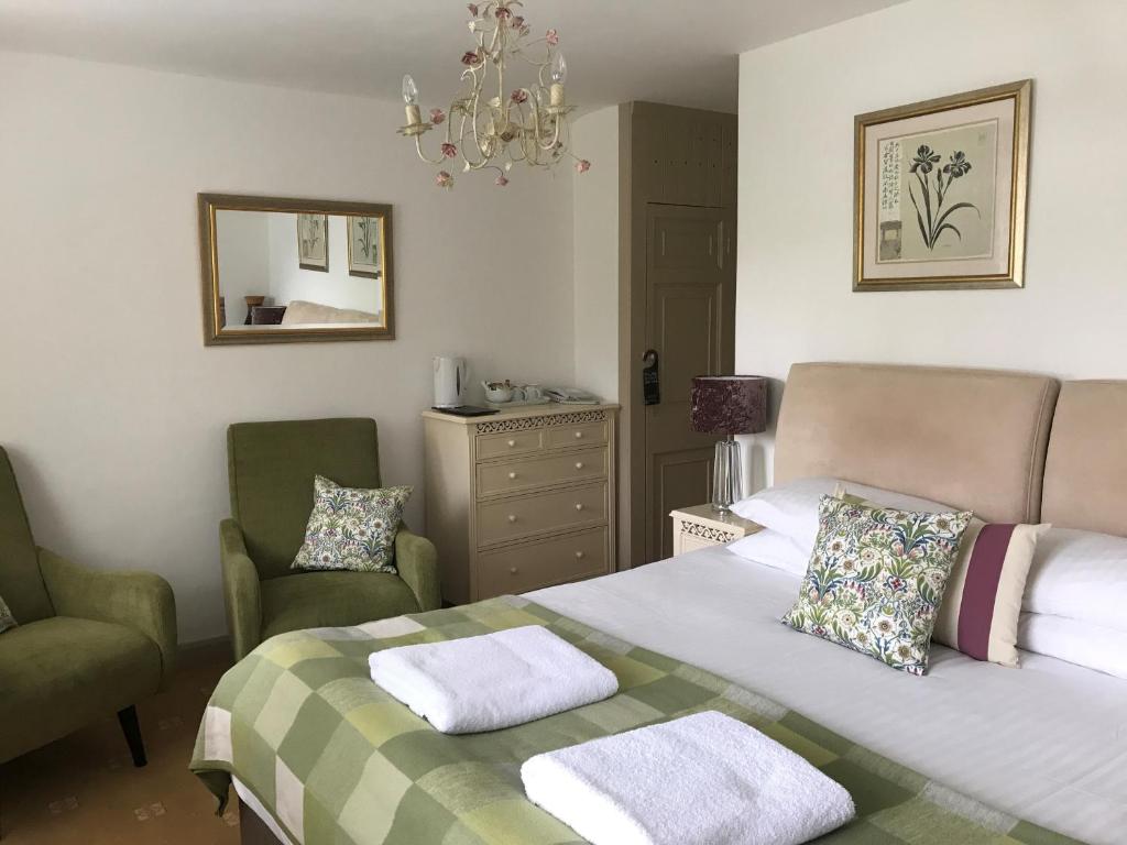 a bedroom with a bed and two chairs and a mirror at Combe House Hotel in Holford