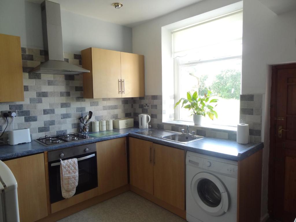 a kitchen with a sink and a washing machine at Fell Cottage in Keighley