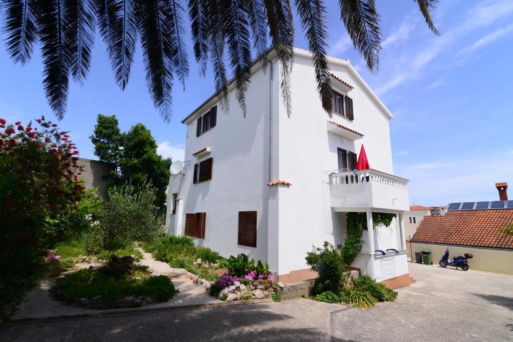 ein weißes Haus mit einer Palme in der Unterkunft Apartments Ana in Mali Lošinj