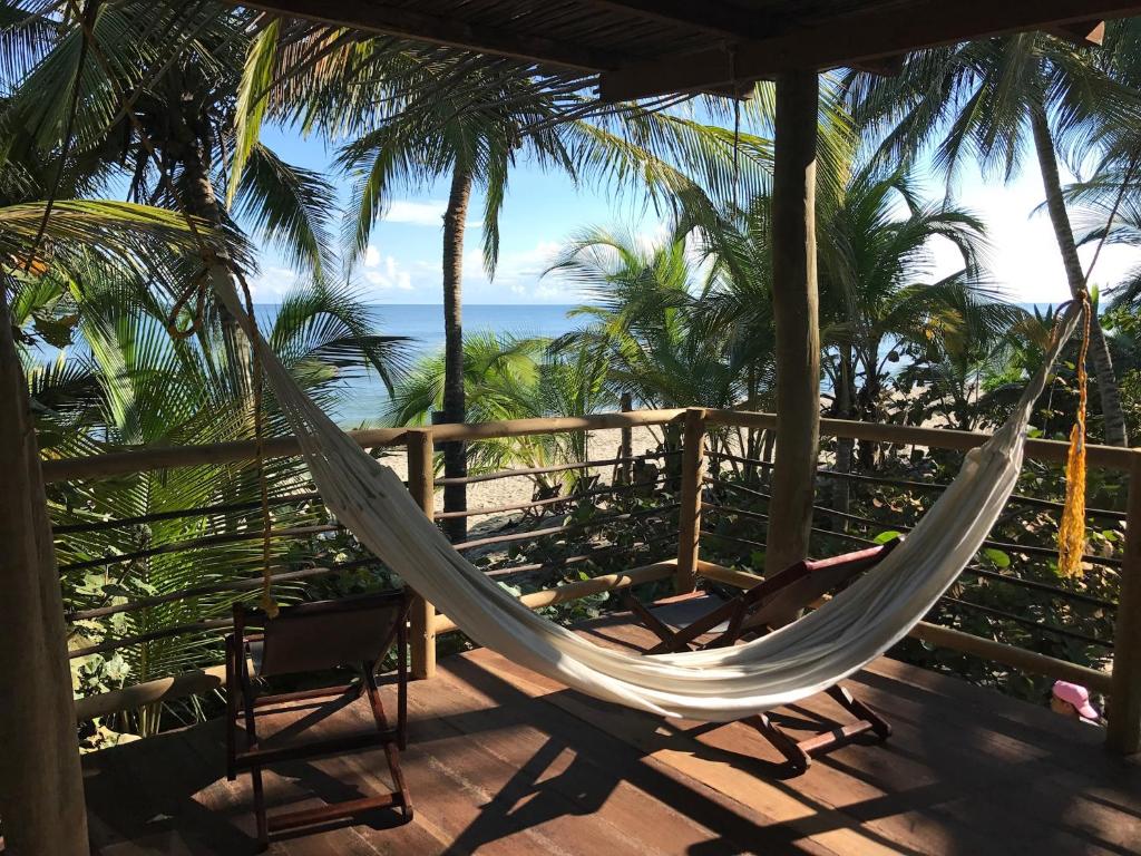 a hammock on a porch with a view of the ocean at Playa Pikua Ecolodge in Guachaca