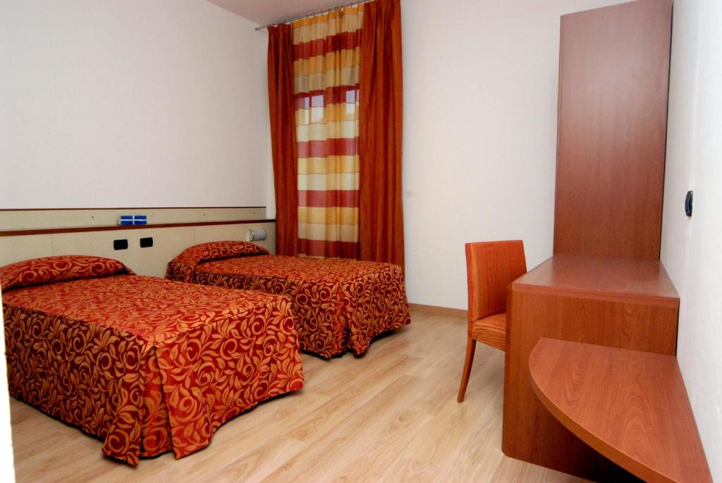 una camera d'albergo con due letti e un tavolo di Hotel Eolo a Sermide