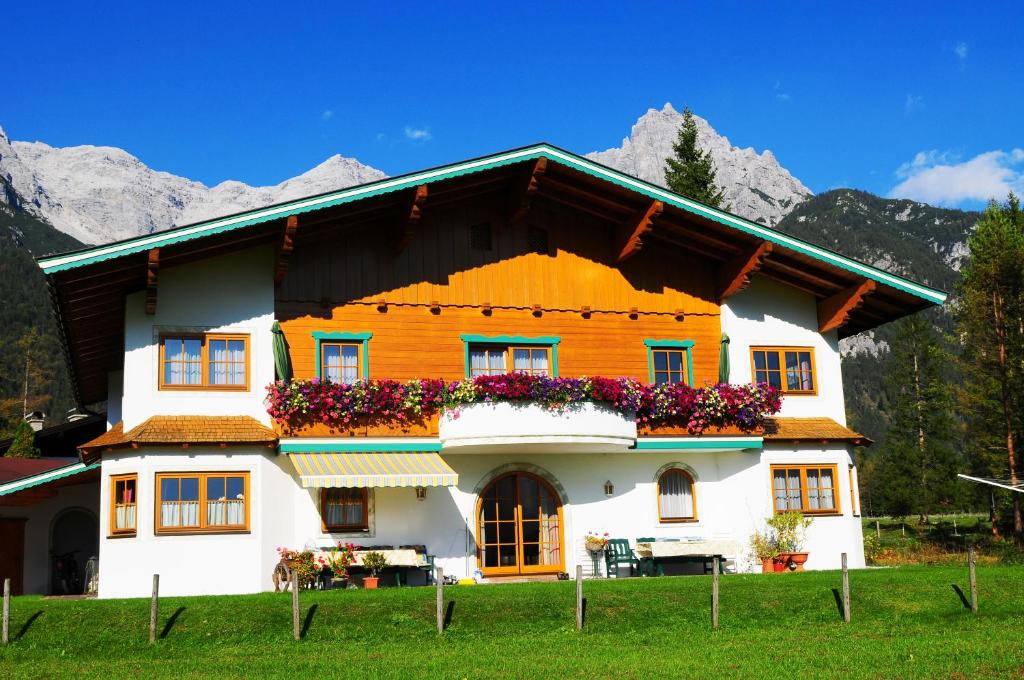 ein Haus mit Blumen vor einem Berg in der Unterkunft Ferienwohnung Simair in Sankt Ulrich am Pillersee