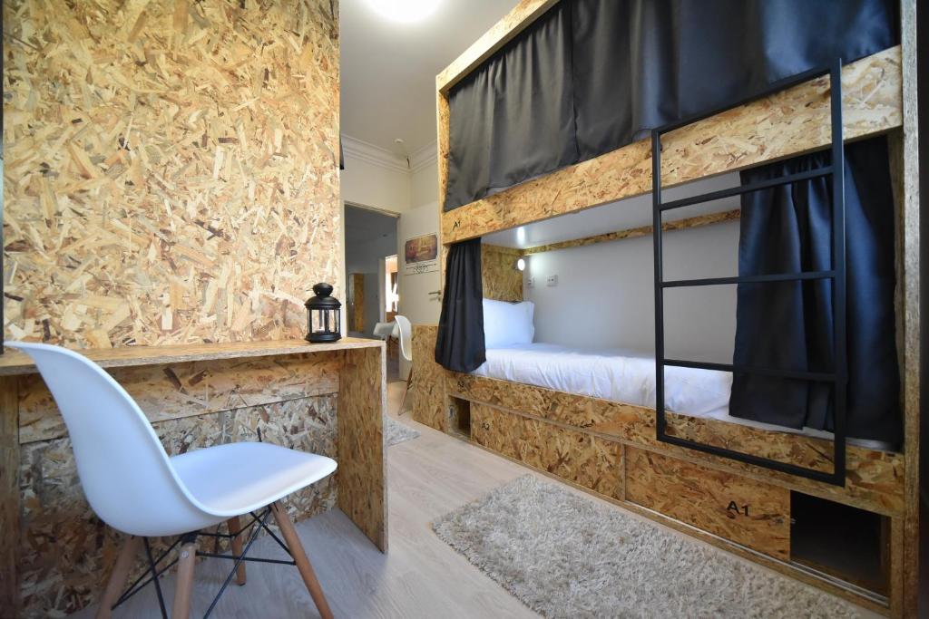 リスボンにあるS ＆ S ホステルの二段ベッドと白い椅子が備わる客室です。
