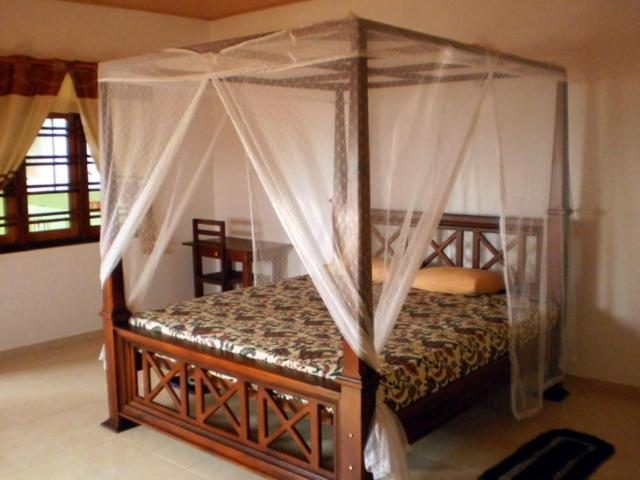 a bedroom with a bed with a canopy at Budde's Beach Restaurant & Guesthouse in Hikkaduwa