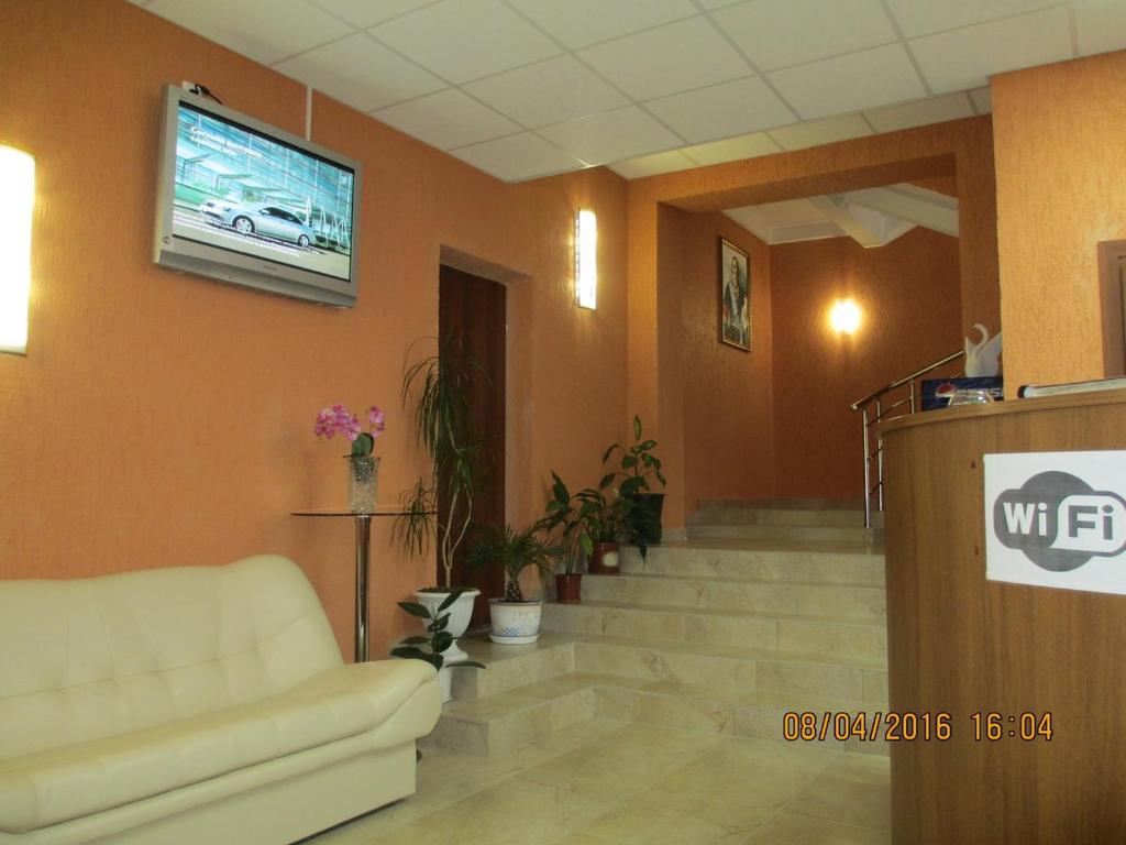 a lobby with a couch and a tv on the wall at Petrovsky Hotel in Lodeynoye Pole