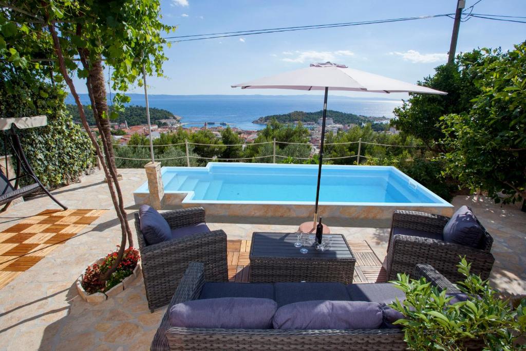 patio z krzesłami, parasolem i basenem w obiekcie Villa Sukara w Makarskiej