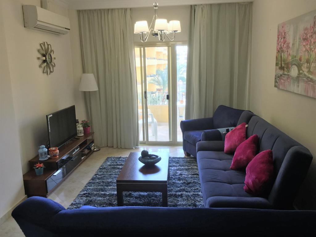 a living room with a blue couch and red pillows at Pool View Apartments at British Resort - Unit 15 in Hurghada