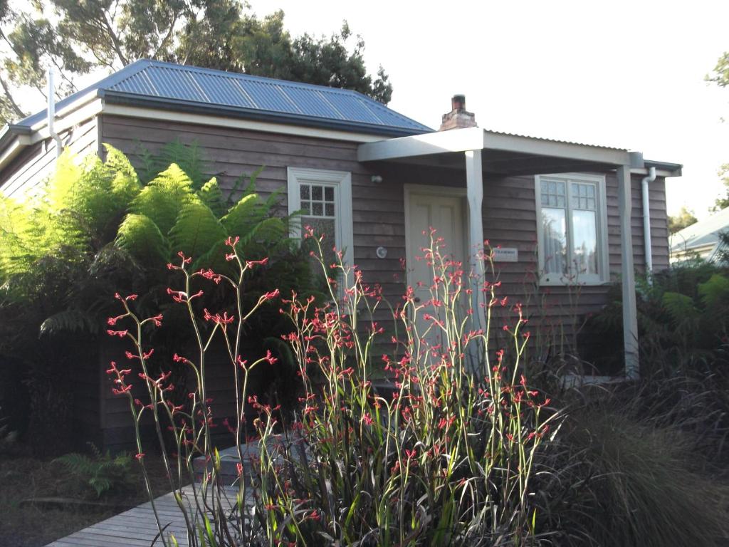 una pequeña casa con un panel solar en el techo en Tramway Cottage, en Strahan