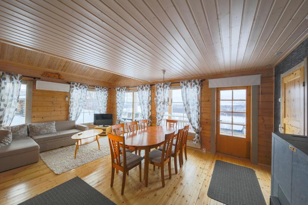 uma sala de estar com uma mesa e cadeiras e um sofá em Arctic Aurora Borealis cottages em Nuorgam