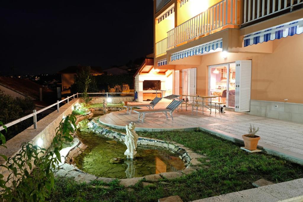 uma casa com uma fonte no quintal à noite em Villa Wind em Okrug Gornji