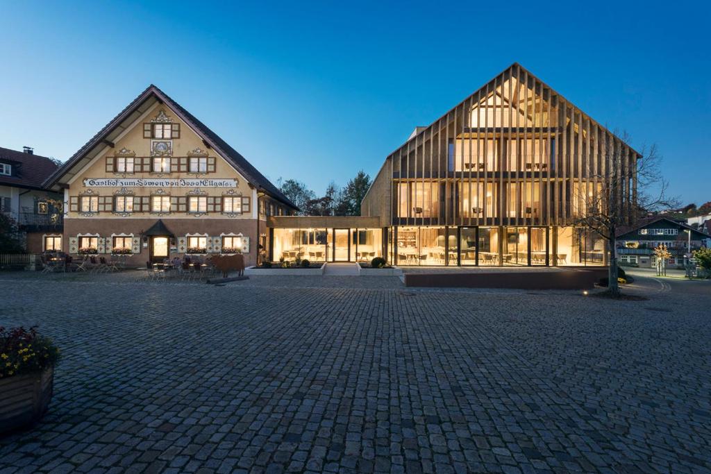 a large wooden building with lights on at Ellgass Allgäu Hotel in Eglofs