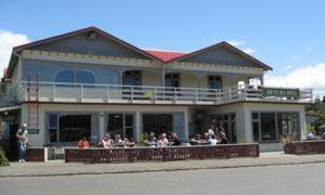 a large building with people sitting on a balcony at South Sea Hotel - Stewart Island in Half-moon Bay