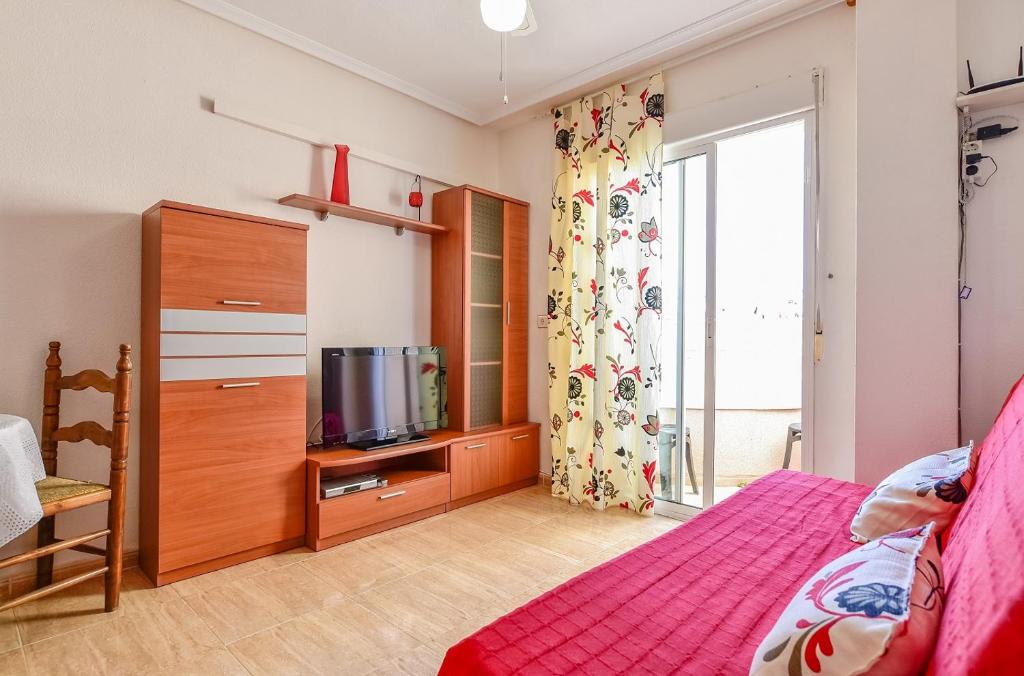 Schlafzimmer mit einem Bett und einem Schrank mit einem TV in der Unterkunft Apartment Finlandia in Torrevieja