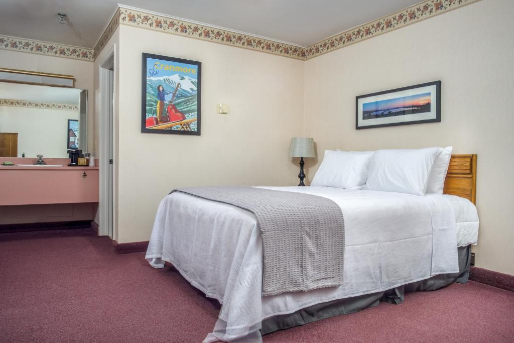 a hotel room with a bed, desk and a painting on the wall at Mountain Village Lodge in Bethel