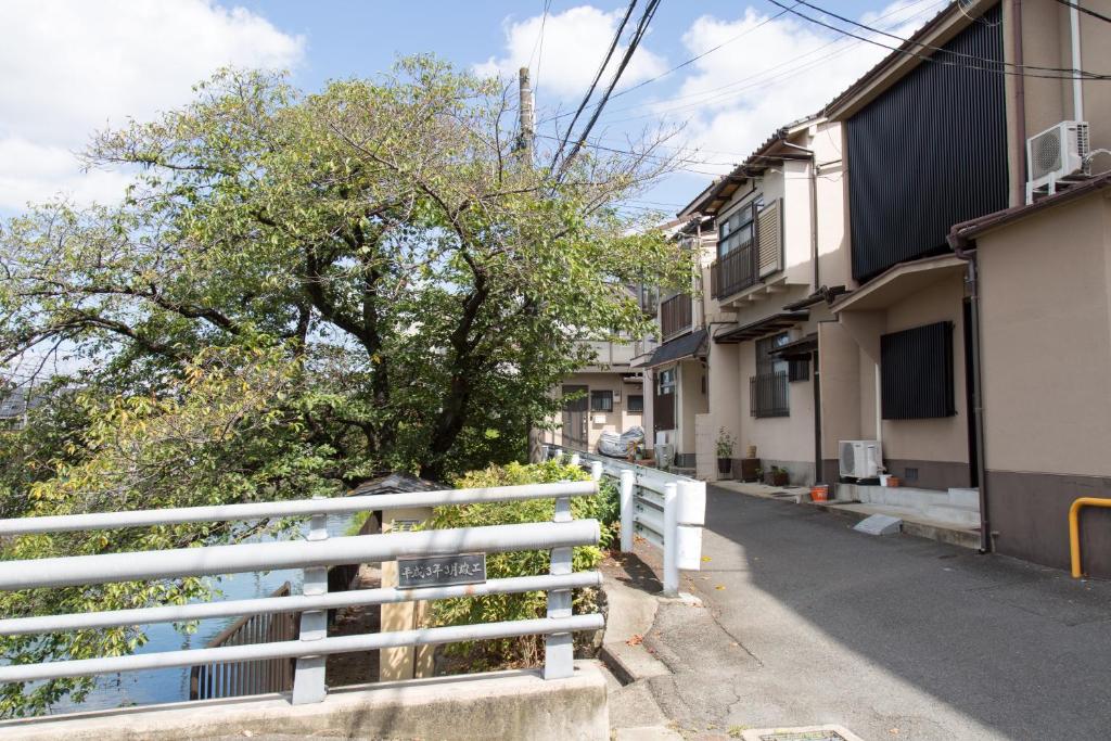 a white fence in front of a house with a tree at Aoi-Riverside Old Townhouse in Kyoto